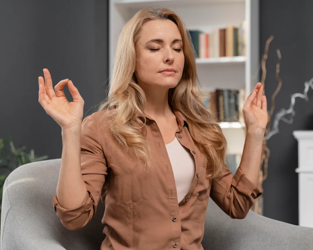 A woman sitting quietly with her eyes closed, in a calm and focused state of attention